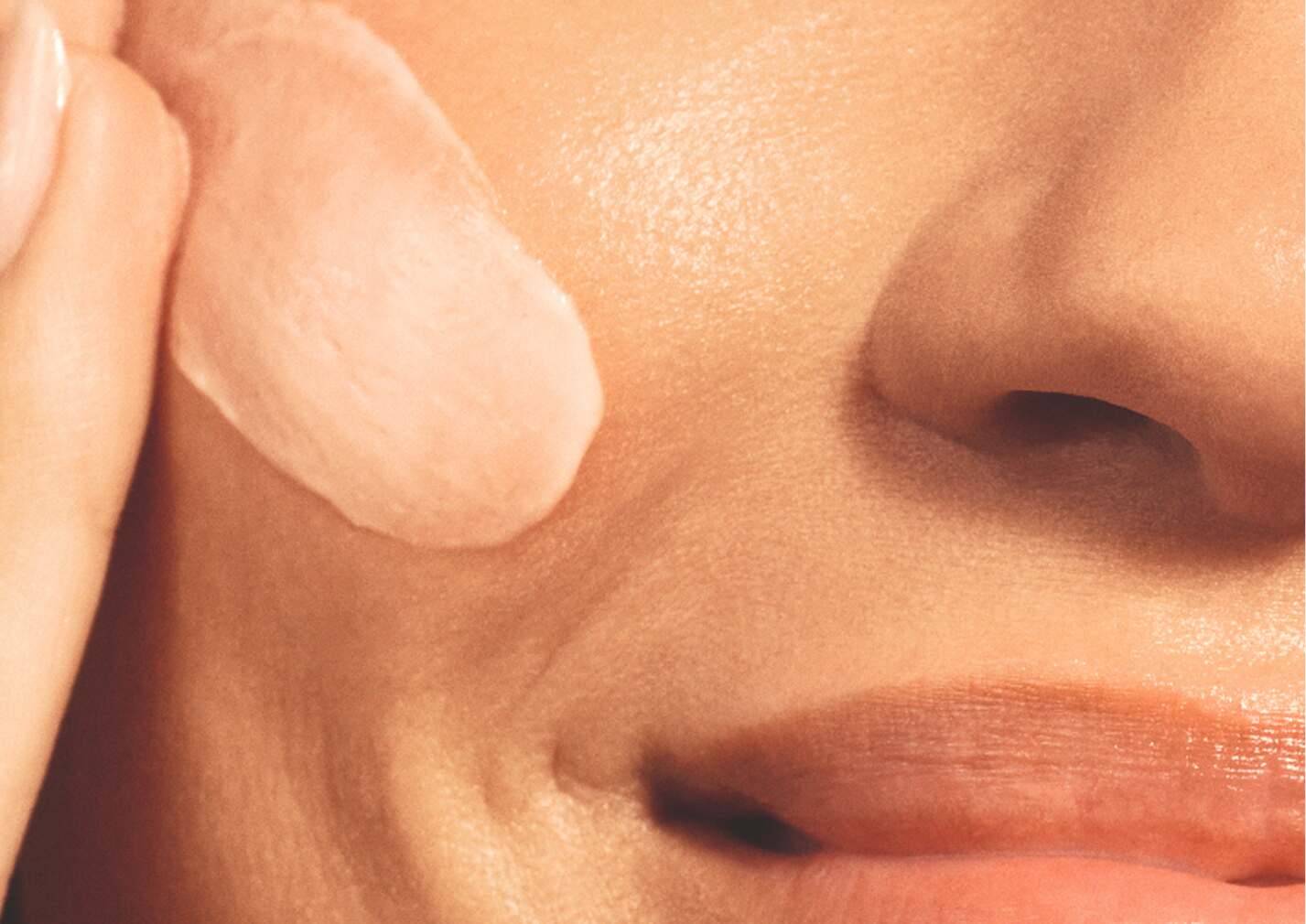 Woman spreading cream on her face